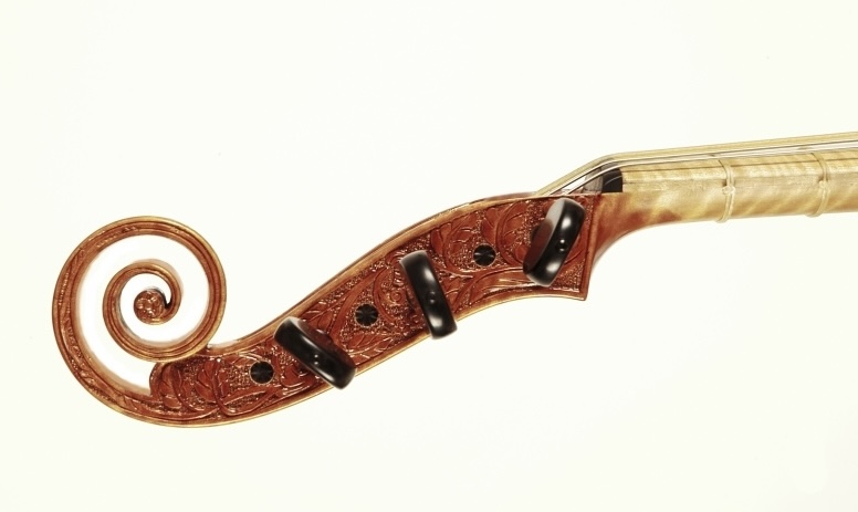 Ornate carved viol scroll detail, baroque woodwork in warm tones